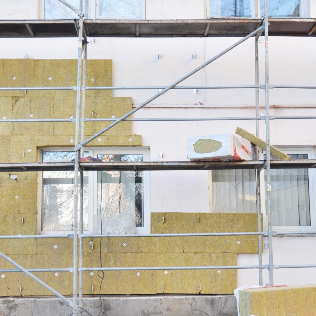 House external wall renovation with mineral wool insulation boards outdoors. External solid wall insulation with mineral wool during house facade walls repair and renovation.